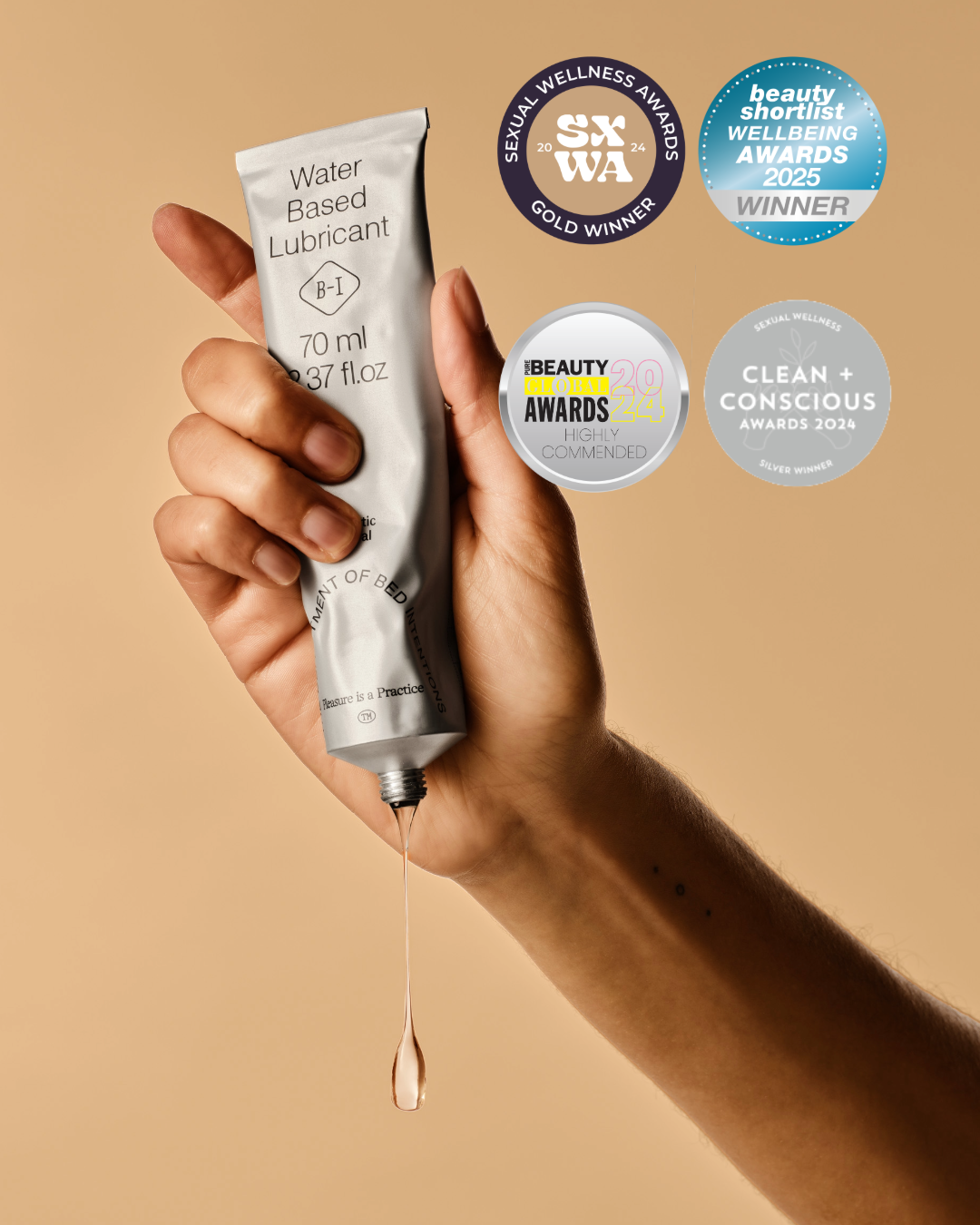 Hand holding a tube of water-based lubricant with awards displayed on a beige background